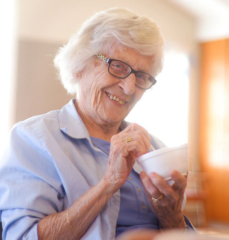 Happy senior woman with ice cream - Andrews Senior Care