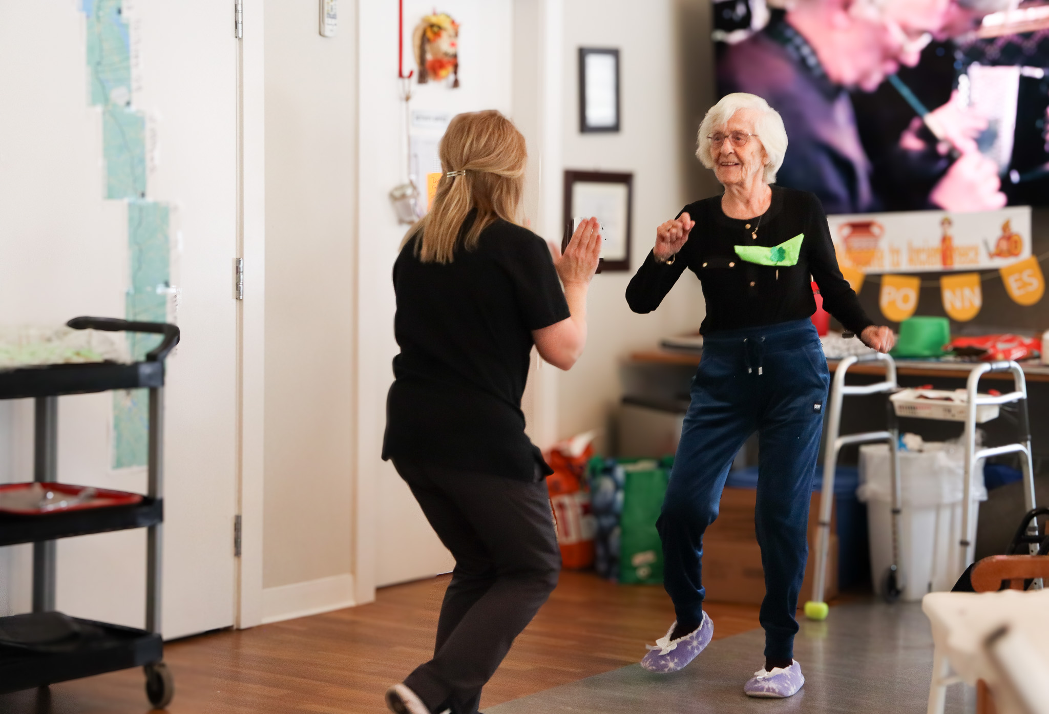 Two ladies dancing beside a walker at Andrews Senior Care retirement home.